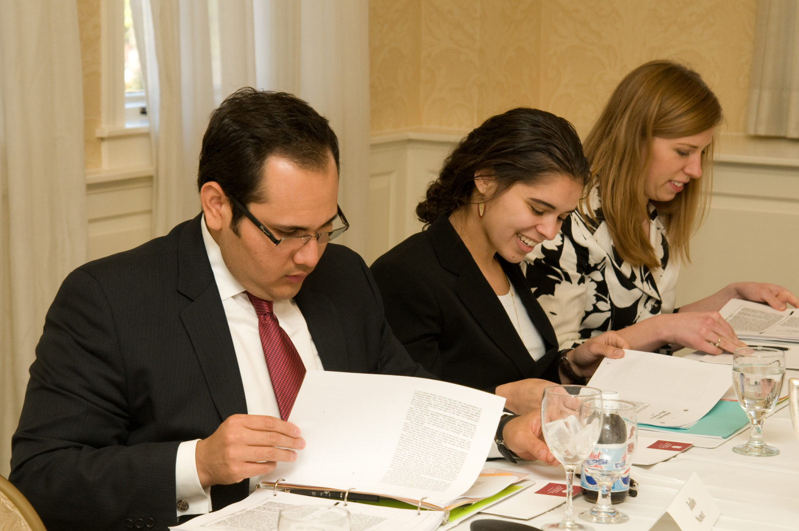 (l.-r.) Julio Nunez (J 08), Christina Mandour-Brackin (HK 08) and Rochelle Olson (B 08) look over the reading materials during Eric Daniels' session on “What would Ayn Rand say about the Economic Crisis.”