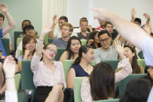 Students in classroom with hands raised