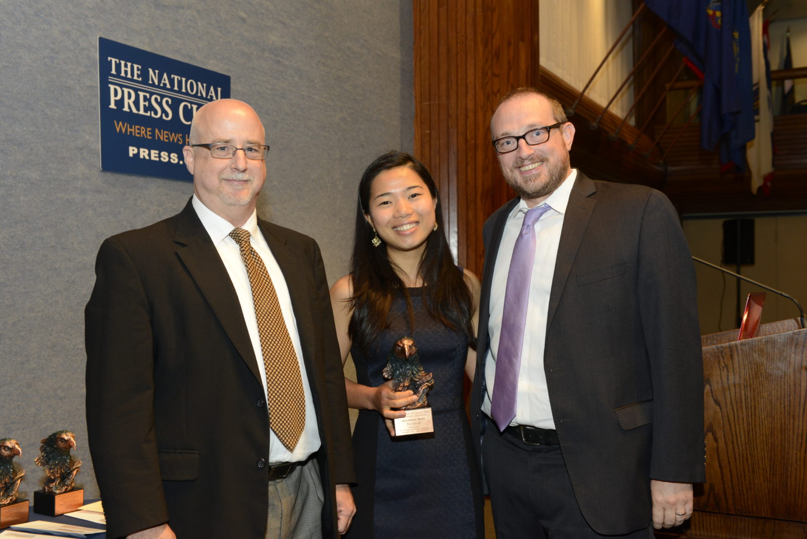 John Merline (right) of the IPJ Board of Visitors presents the 2014 Excellence in Economic Reporting Award to Aki Ito (center) of Bloomberg News at the annual Journalism Awards Ceremony at the National Press Club.      