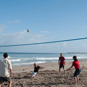 Alumni enjoy a beach volleyball game outside of the Four Seasons.