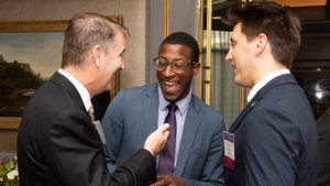 Three men standing together, talking and laughing at a dinner reception at the 2018 Annual Conference.
