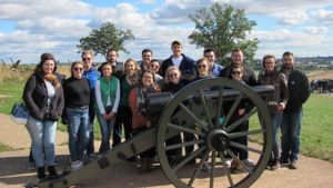 The group of the 2018-19 Public Policy Fellowship Fellows gather behind a Civil War canon for a group photo.
